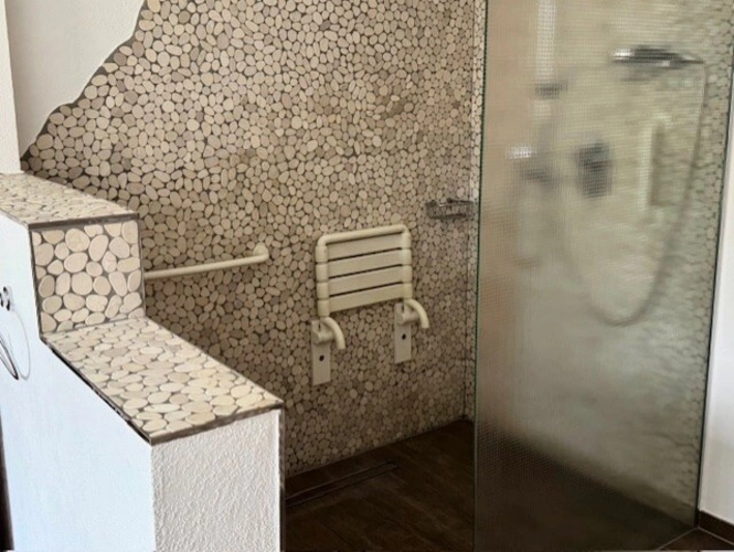 Die sehr geräumige, bodengleiche Dusche mit Glasabtrennung