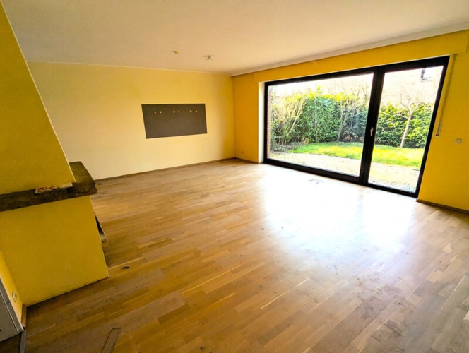 Das große Wohnzimmer mit der Panoramascheibe und dem Blick in den Garten
